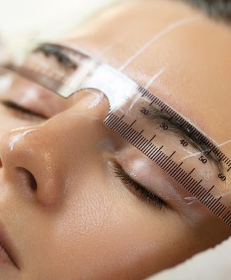 Woman during professional eyebrow mapping procedure